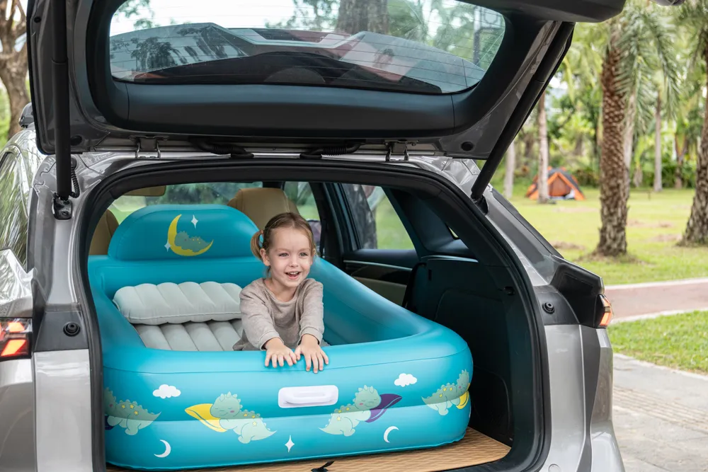 Girl smiling in the Quooly bed set up in a car trunk